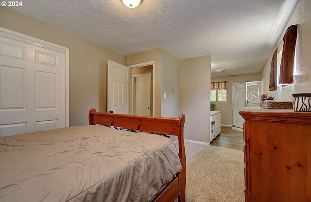 carpeted bedroom featuring a textured ceiling and connected bathroom