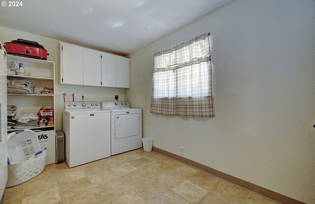 clothes washing area featuring light tile patterned floors, cabinets, and separate washer and dryer