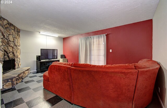 living room featuring a textured ceiling, a fireplace, and tile patterned flooring