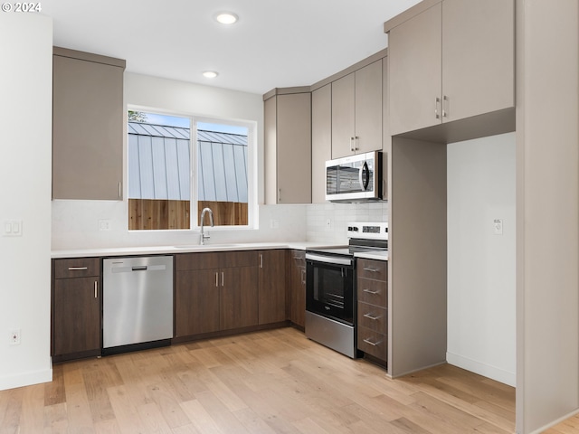 kitchen featuring backsplash, sink, stainless steel appliances, and light wood-type flooring