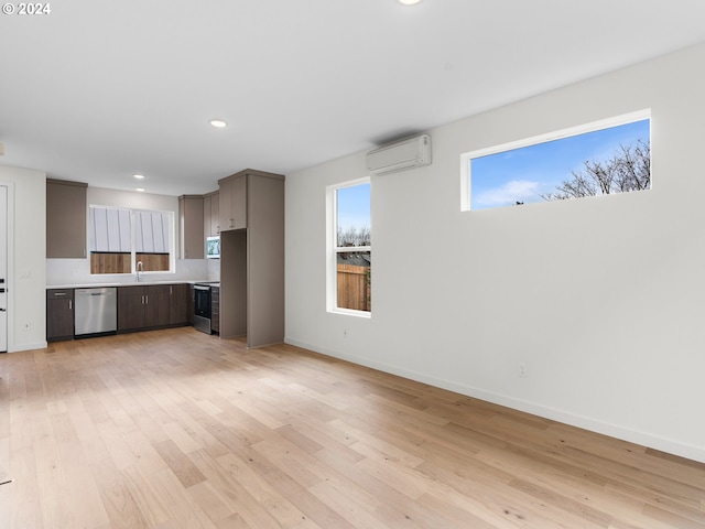 unfurnished living room with light wood-type flooring, an AC wall unit, and sink