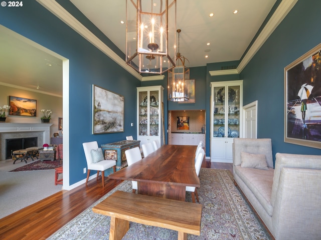 dining area with baseboards, ornamental molding, wood finished floors, a fireplace, and a chandelier