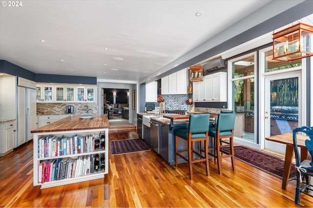 kitchen featuring an island with sink, light wood-type flooring, butcher block countertops, and white cabinets