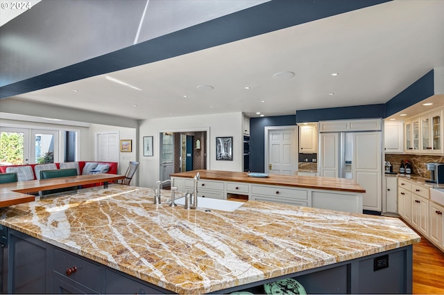 kitchen featuring butcher block counters, a spacious island, tasteful backsplash, and a sink