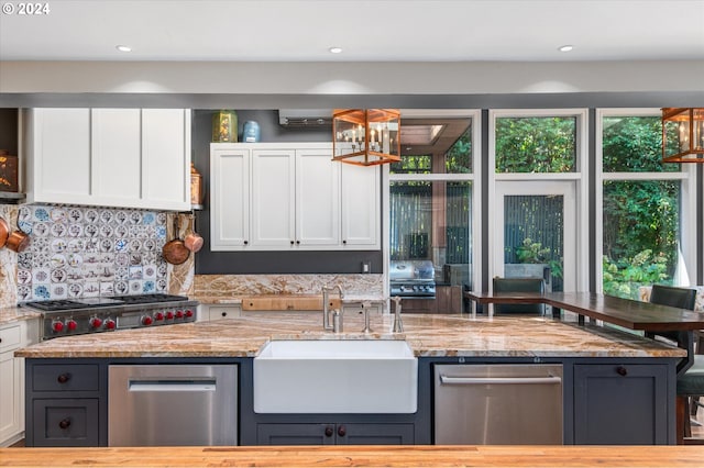 kitchen featuring light stone counters, tasteful backsplash, recessed lighting, white cabinetry, and a sink