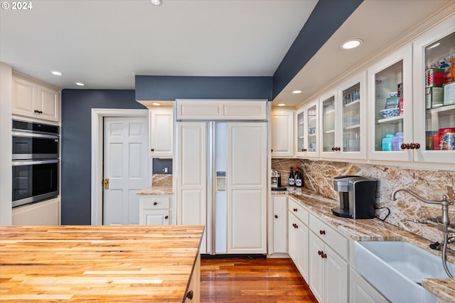 kitchen featuring double oven, white cabinets, paneled fridge, and a sink