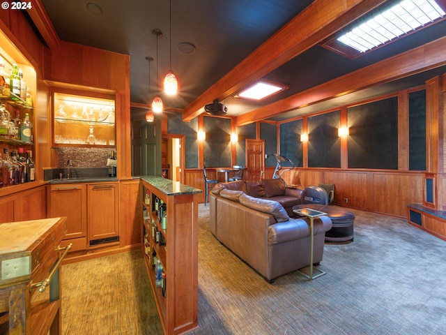 cinema room featuring a wainscoted wall, a sink, carpet flooring, beam ceiling, and wet bar