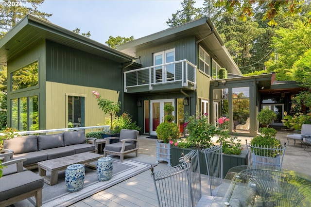 back of property with an outdoor living space, a balcony, and french doors