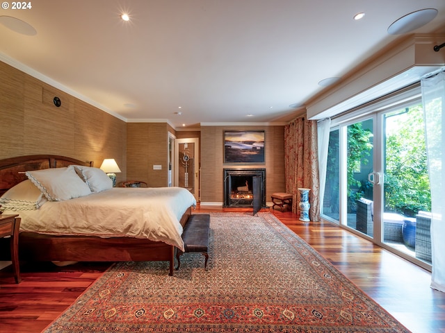 bedroom with wood finished floors, access to outside, a lit fireplace, crown molding, and recessed lighting