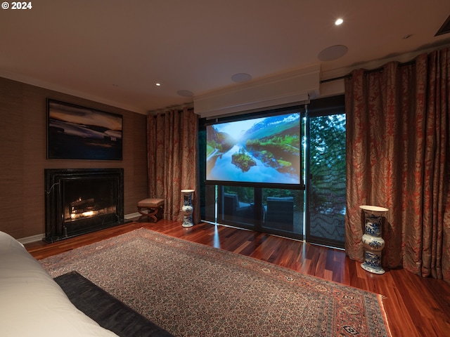 home theater with ornamental molding, recessed lighting, a lit fireplace, and wood finished floors