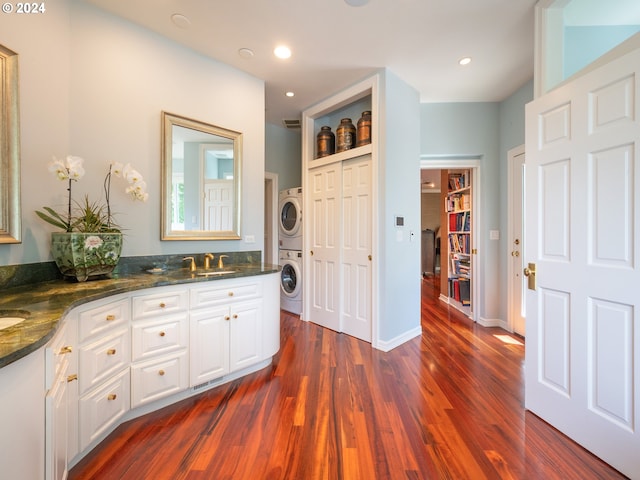 full bath featuring a sink, stacked washing maching and dryer, double vanity, and wood finished floors