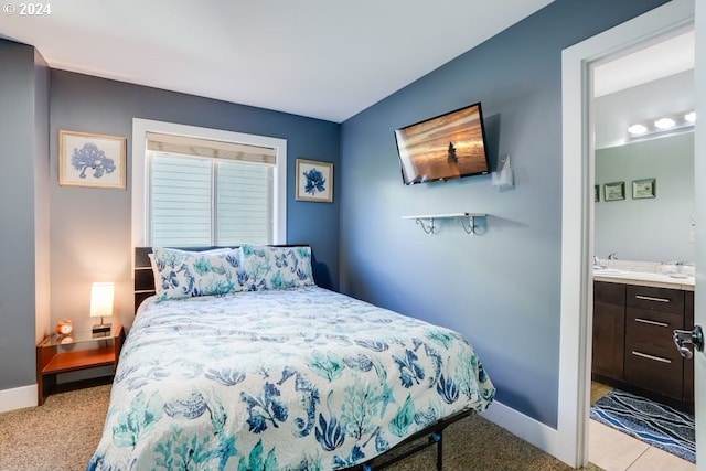 bedroom featuring sink, ensuite bathroom, and light colored carpet