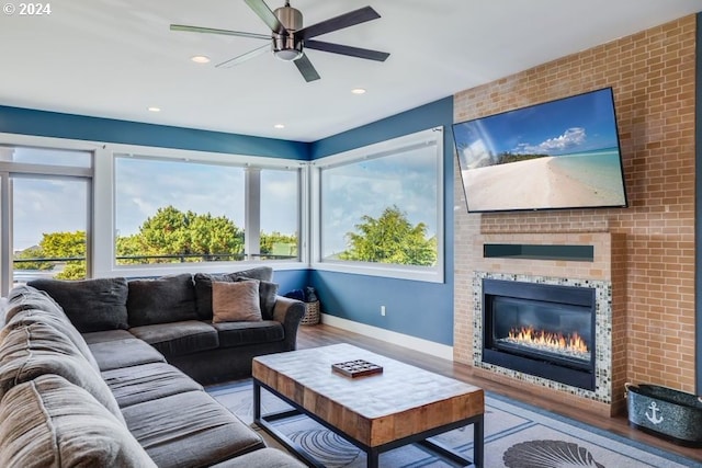 living room featuring light hardwood / wood-style flooring, a brick fireplace, and ceiling fan