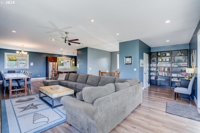 living room with ceiling fan with notable chandelier and light wood-type flooring