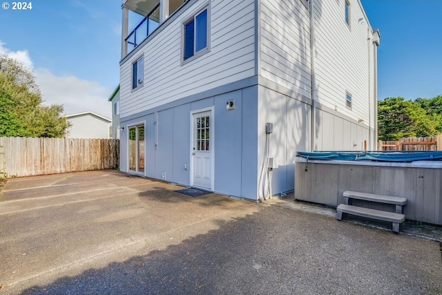 view of side of property with a patio and a hot tub