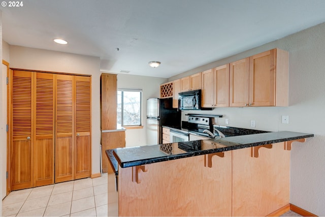 kitchen featuring light tile patterned flooring, a kitchen bar, kitchen peninsula, stainless steel appliances, and light brown cabinets