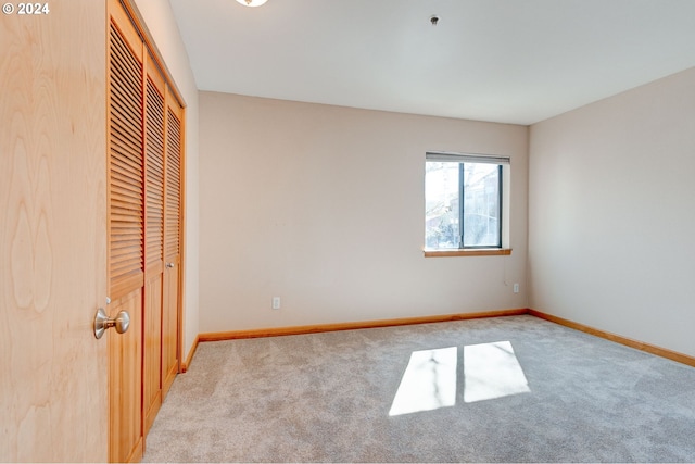 unfurnished bedroom featuring light carpet and a closet