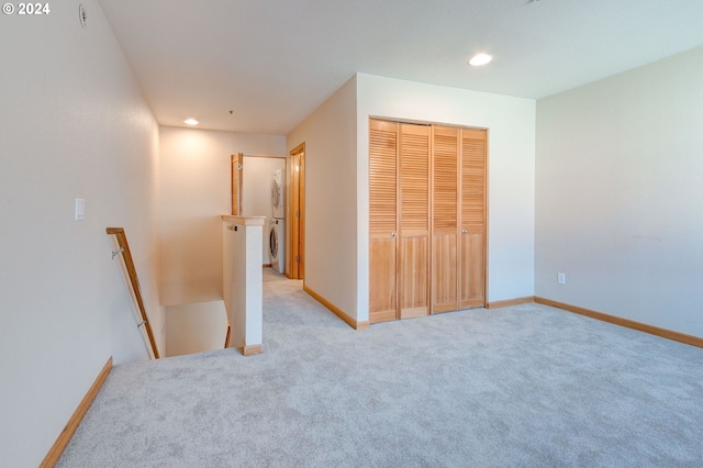 unfurnished bedroom featuring light carpet, stacked washer and clothes dryer, and a closet