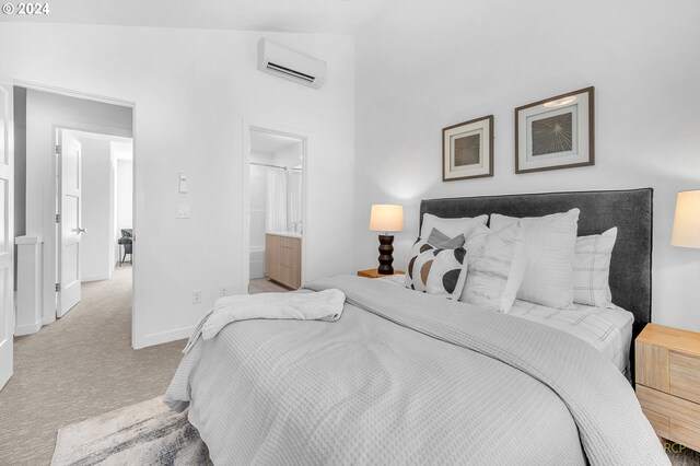 bedroom featuring light colored carpet, lofted ceiling, an AC wall unit, and ensuite bathroom