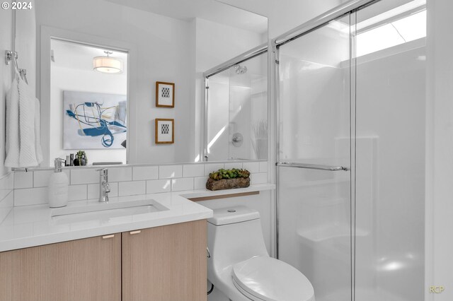 bathroom featuring vanity, backsplash, an enclosed shower, and toilet