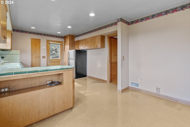 kitchen featuring fridge and tile countertops