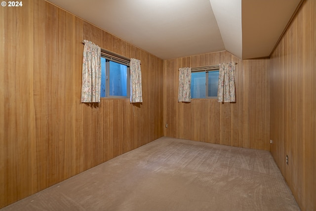 spare room with carpet flooring, vaulted ceiling, and wood walls