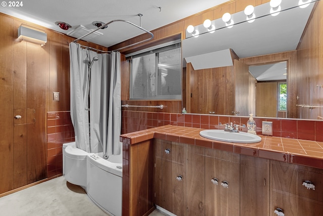 bathroom featuring vanity, shower / bath combination with curtain, backsplash, and wood walls