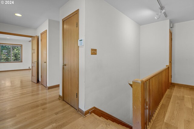 hall with light hardwood / wood-style flooring and track lighting