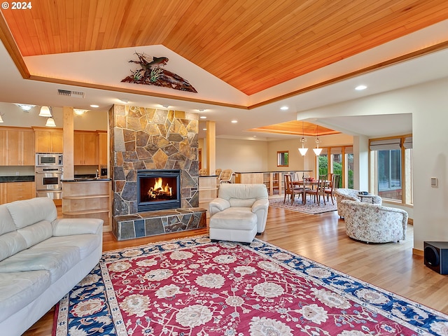 living room featuring hardwood / wood-style floors, vaulted ceiling, wooden ceiling, and a stone fireplace