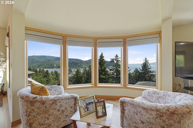 sitting room featuring a wealth of natural light, a water and mountain view, and light hardwood / wood-style flooring