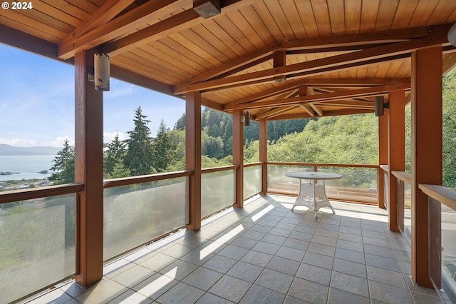 unfurnished sunroom featuring vaulted ceiling with beams, a water view, and wood ceiling