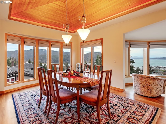 dining space featuring a water and mountain view, wood ceiling, lofted ceiling, and light hardwood / wood-style floors