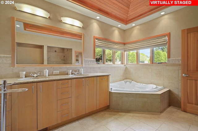 bathroom featuring tiled tub, tile patterned flooring, vanity, and a healthy amount of sunlight