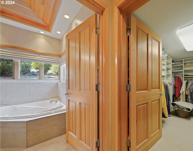 bathroom featuring tile patterned floors, a relaxing tiled tub, and lofted ceiling