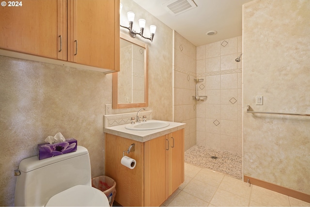 bathroom with a tile shower, tile patterned flooring, vanity, and toilet