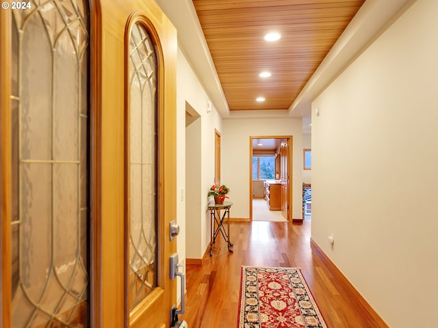 corridor with light hardwood / wood-style floors and wood ceiling