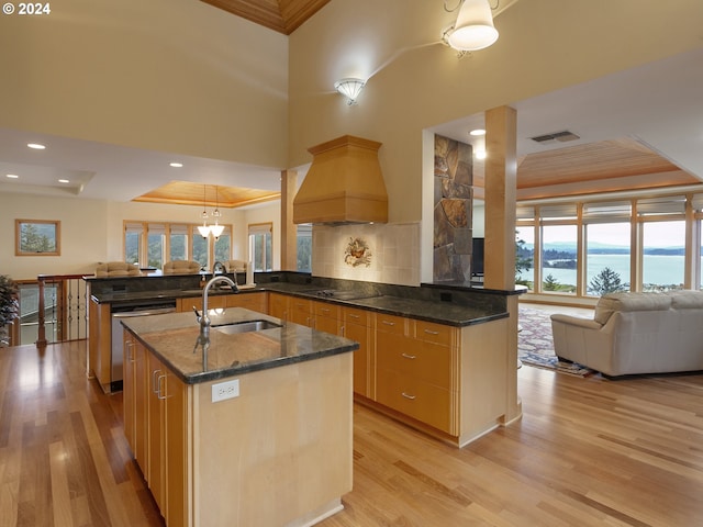 kitchen with a water view, kitchen peninsula, premium range hood, and a tray ceiling