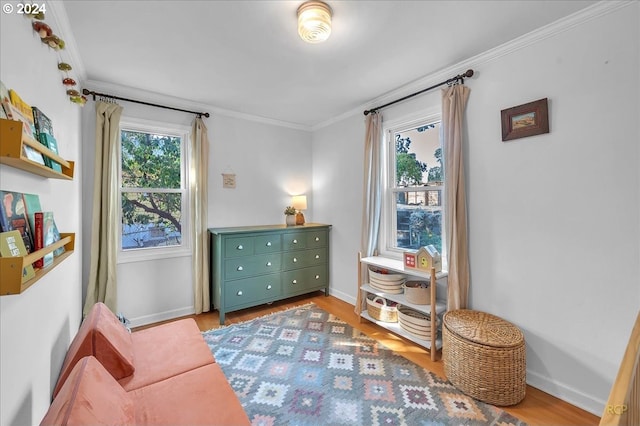 living area with light hardwood / wood-style flooring and ornamental molding