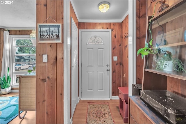 foyer with light hardwood / wood-style flooring, wood walls, and crown molding