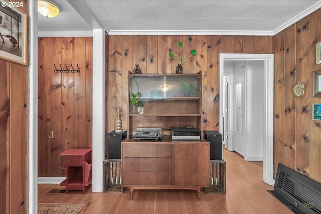 home office featuring light wood-type flooring, wooden walls, and a textured ceiling