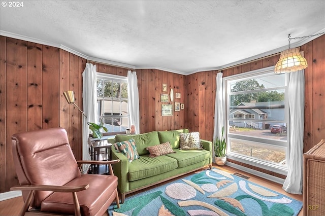 living area featuring hardwood / wood-style flooring, a wealth of natural light, a textured ceiling, and wooden walls