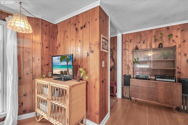 office area with wood walls, wood-type flooring, a textured ceiling, and ornamental molding