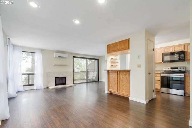 unfurnished living room featuring a tile fireplace, dark hardwood / wood-style flooring, and a wall mounted AC