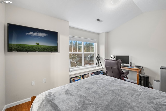 bedroom with a textured ceiling, hardwood / wood-style floors, and lofted ceiling