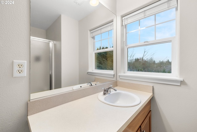 bathroom with walk in shower, vanity, and plenty of natural light