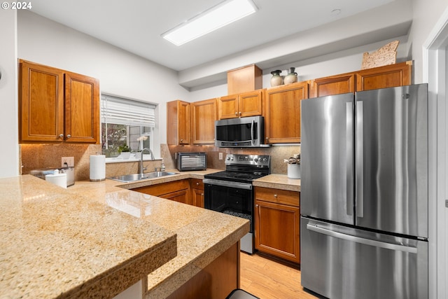 kitchen featuring decorative backsplash, appliances with stainless steel finishes, light hardwood / wood-style floors, and sink