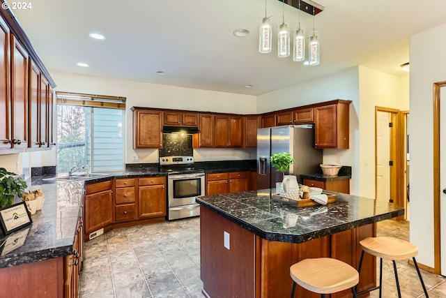 kitchen featuring sink, a center island, pendant lighting, a kitchen bar, and appliances with stainless steel finishes