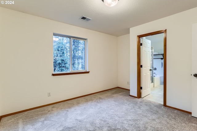 unfurnished bedroom with a walk in closet and light carpet