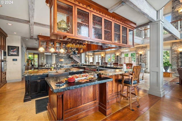 bar with dark stone counters, beamed ceiling, stainless steel oven, and sink