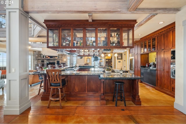 bar featuring a stone fireplace, beam ceiling, and stone countertops